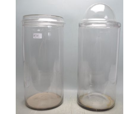 A pair of large vintage retro 20th century glass confectionery jars. The jars of a large cylindrical form made of clear glass