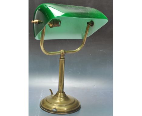 A 20th Century vintage bankers desk / table lamp light of brass construction having an adjustable green glass shade supported