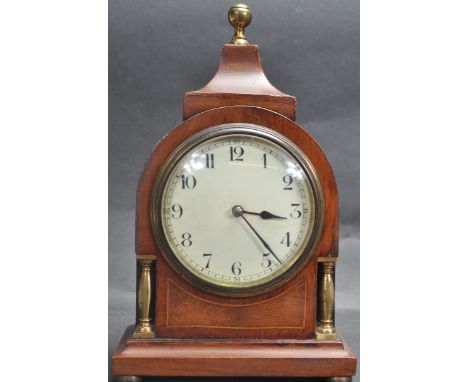 An Edwardian mahogany line inlaid 8-day mantel clock. Of unusual form having brass column and finial top, ceramic dial with a