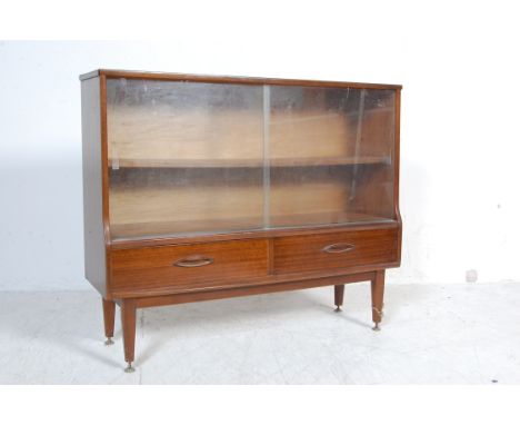 A vintage retro mid 20th century circa 1960’s teak wood bookcase / display cabinet. The bookcase having twin glass sliding do