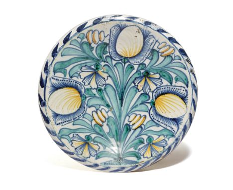 A DELFTWARE POTTERY TULIP CHARGER LONDON, C.1670-85 boldly painted in green, blue and ochre with a design of tulips and carna