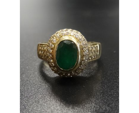 EMERALD AND DIAMOND CLUSTER DRESS RING the oval cut emerald approximately 0.9cts in multi diamond surround and with further d