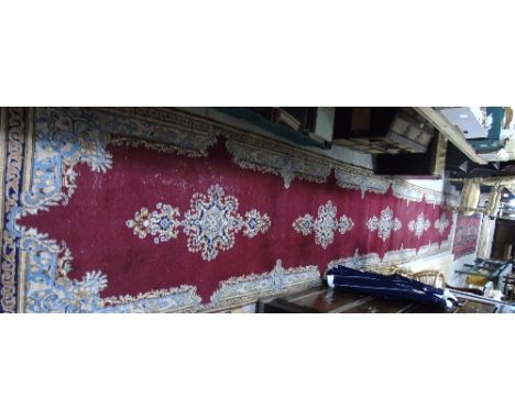 A Kerman Persian Runner on Red Ground, approx 22ft 10ins x 2ft 10ins.