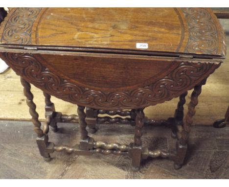 A carved circular oak gate leg table on barley twist legs approx 2'3 diameter 