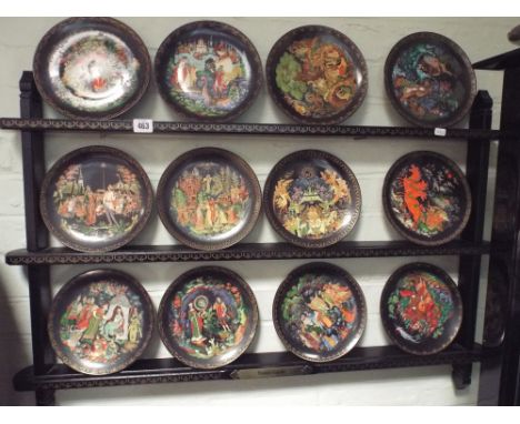 A set of 12 decorative Russian plates on display shelf 