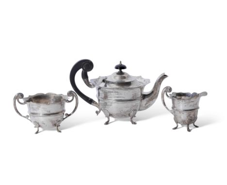 Edwardian three piece silver tea set of circular form with card cut rims, flying scroll handles, raised body bands, each item