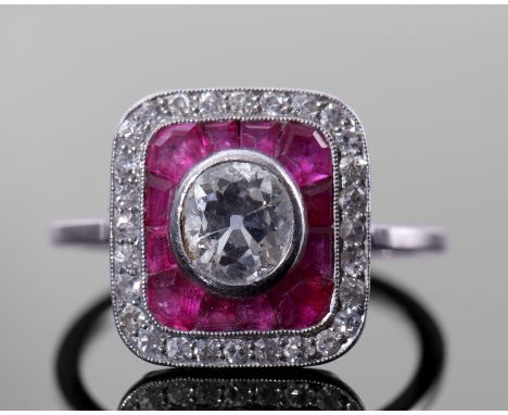 Diamond and calibre ruby target ring comprising a rub-over central old cut diamond, 0.70ct approx, surrounded by pave set cal