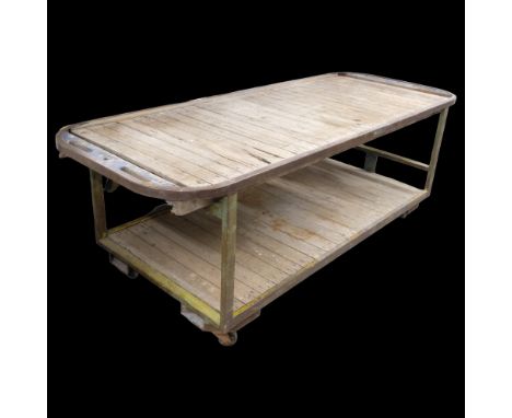 A very large two-tier industrial work bench / shop display table, with cast iron frame, pine slats and raised on casters. 285