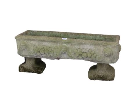 A weathered concrete rectangular garden planter, raised on two feet, with figural and floral decoration. 87x36x28cm.This is i