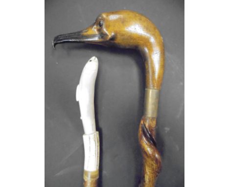 A walking stick with handle carved as a fish, a further walking stick with handle carved as an eagle's head and one shooting 