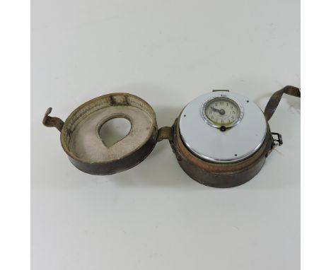 An early 20th century pigeon clock, in a leather case, 14cm diameter
