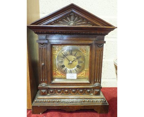 An Edwardian carved oak architectural form mantel clock with silvered chapter ring and gong-striking movement, 40cm high.