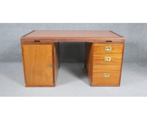 A mid century teak pedestal desk with pull out slides and inset brass military style handles, stamped Waring and Gillows. H.7