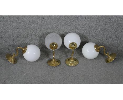 Four vintage brass wall mounted lights with globe shades. Three with opaque milk glass shades and one frosted with engraved g