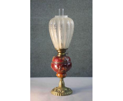 A Victorian relief ceramic and repousse brass rose design oil lamp. With etched tear drop shaped frosted glass shade. H.57 Di