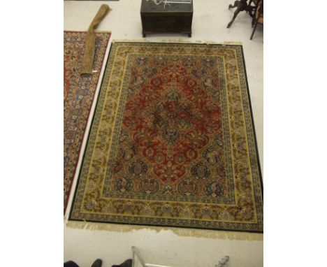 A Persian style machine made carpet, the central medallion in blue, mustard and red on a red floral patterned ground within m