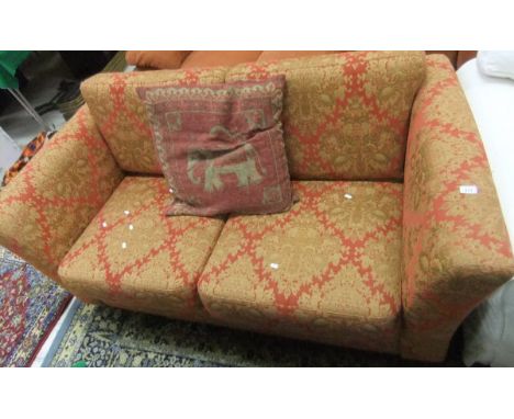 A modern two seat sofa with red and gold damask style upholstery