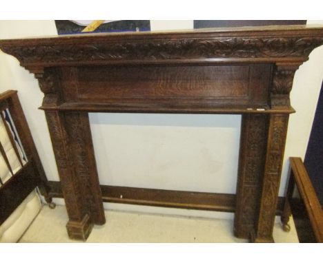 A carved oak fire surround / mantelpiece with all-over acanthus and mask decoration in the Gothic Revival taste