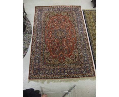 A Persian carpet, the central medallion in blue, terracotta and cream on a terracotta, stylised floral decorated ground, with