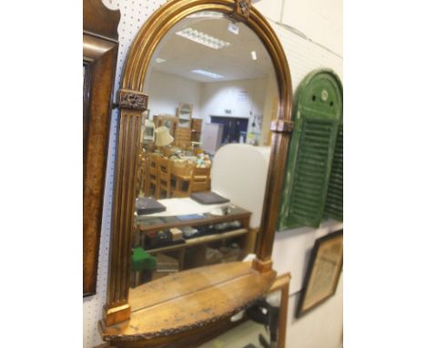 A modern gilt arched framed wall mirror with shelf and another gilt framed rectangular wall mirror