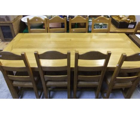 An oak rectangular dining table, and eight ladder back rush seated dining chairs