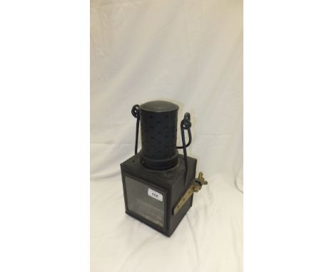 A black railway lamp with brassed hinges and screw closing mechanism