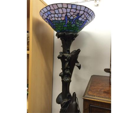 A modern ornate standard lamp decorated with dolphins leaping and a Tiffany style lampshade