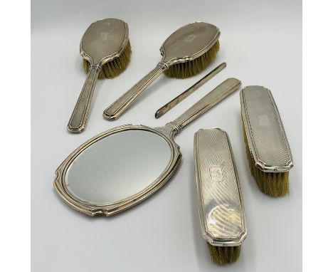 A silver backed dressing table set, comprising four brushes, hand mirror and comb back. Estimate £40-60.