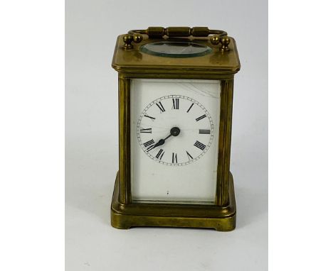 An early 20th century brass carriage clock timepiece with bevelled glass panels and an enamelled face with Roman numerals and