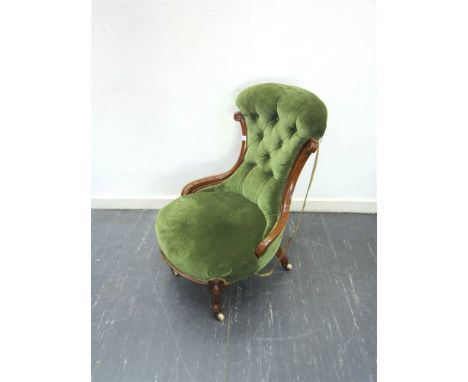 A VICTORIAN BUTTON BACK NURSING CHAIR upholstered in green dralon and raised on cabriole frontal supports with castors
