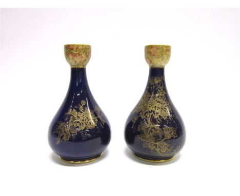 A PAIR OF EARLY 20TH CENTURY CERAMIC VASES with floral decoration in gilt over a dark blue glaze, 20cm high.