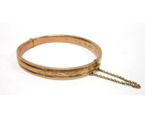 A HINGED BANGLE  stamped 'wax filled' '9ct', of half engraved design and erased cartouche, 11g gross