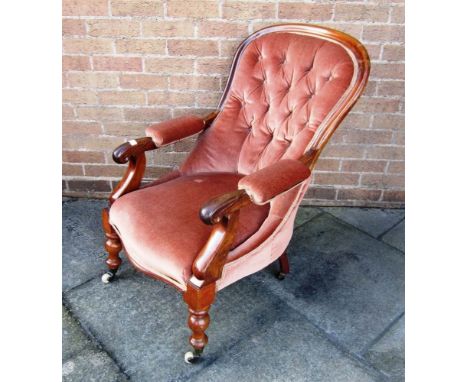 A VICTORIAN UPHOLSTERED BUTTON BACK OPEN ARMCHAIR with turned frontal supports and ceramic castors