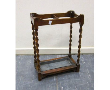 A 1930'S OAK TWO-DIVISION STICK STAND with four spiral supports and drip tray, 63cm high, 47cm wide