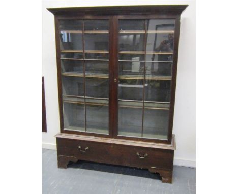 A VICTORIAN MAHOGANY GLAZED BOOKCASE with four shelves, on stand with full front and brass loop handles and raised on bracket