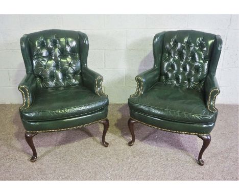 A pair of George III style green leather wing armchairs, 20th century, of compact form, with button upholstered backs and hob