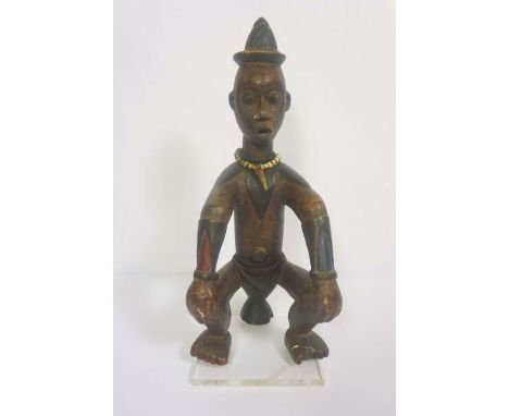 An interesting African tribal carved seated figure, carved naturalistically with light polychromatic paint and seated on a dr