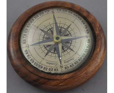 A Victorian style wooden paperweight with floating compass