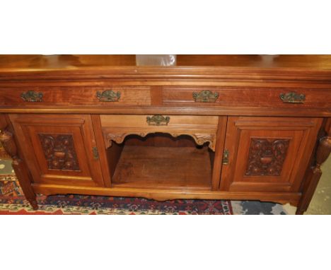 An Edwardian walnut sideboard with an arrangement of three drawers and carved panel doors about and central recess, W. 178.