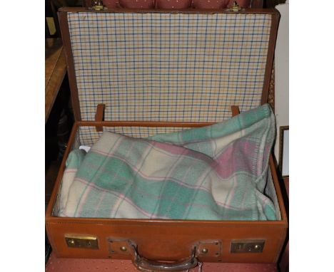 A vintage brass mounted tan leather suitcase containing a welsh tartan blanket