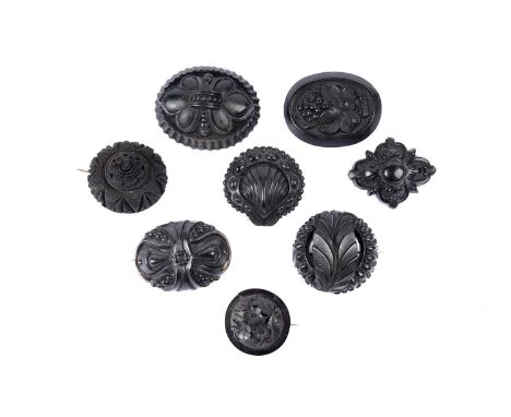 Eight Victorian Romantic Revival jet and faux jet brooches, each of boss form, with botanical or natural devices.