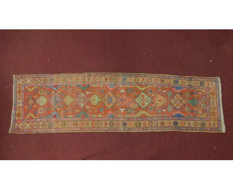 A Belouch runner repeating stylised pole medallion on a rouge field complimented by a stylised geometrical border 293x82cm 