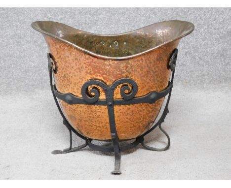 An Art Nouveau beaten copper helmet shaped coal bucket with wrought iron stand. H.37 W.43 D.27cm 