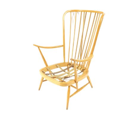 A light Ercol stick back wing chair, raised on slender rounded tapering supports united by stretchers