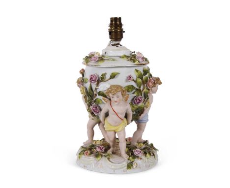 A large continental porcelain lamp base, the lamp base supported by three large cherubs with applied floral decoration, 25cm 