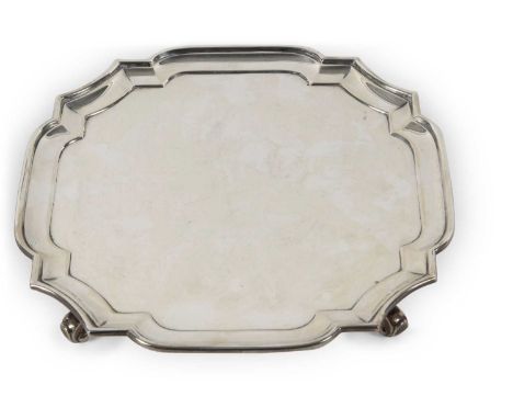  George VI Silver salver of square form having shaped and cut corners with a Chippendale patterned border, supported on four 