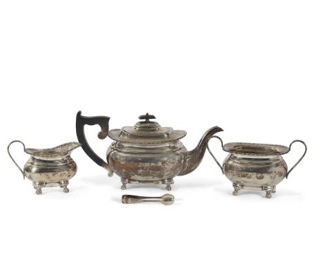 George V silver three piece tea service of plain ovoid tapering form with applied gadrooned edges and supported on four paw f