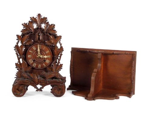 A Black Forest cuckoo clock of typical form, dial surrounded by carved leaf and animal decoration, raised on four scrolled fe