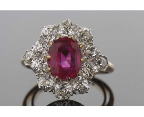 A ruby and diamond cluster ring, the oval claw mounted ruby, approx. 8.8 x 6.8 x 4.0mm, surrounded by old mine cut rubies and