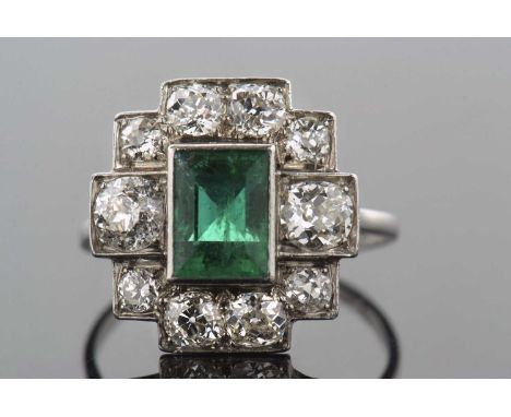 An early/mid 20th century emerald and diamond ring, the central collet mounted step cut emearld, surrounded by old mine and r